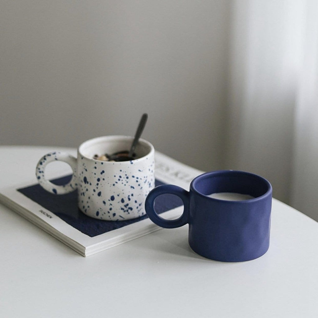 A navy blue ceramic dumbo mug with a textured matte finish and a circular handle