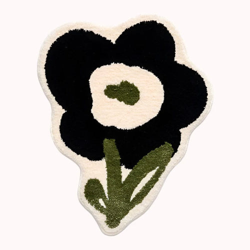 Black flower shaped rug with plush textured surface in black and cream floral design with olive green stem