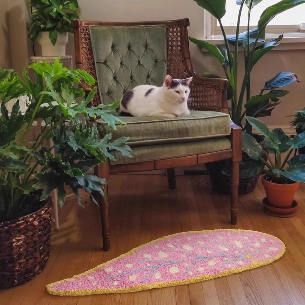 A pink leaf shaped rug with white polka dots and a yellow border perfect for decorative floor use