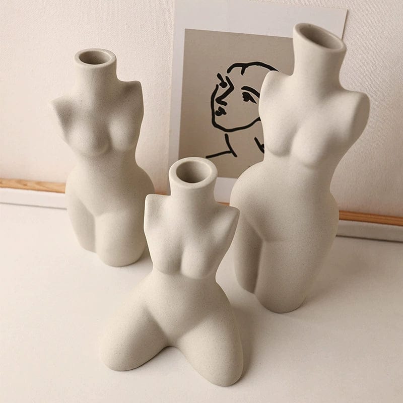 Three minimalist off-white ceramic body shaped vases resembling female torsos for decorative use