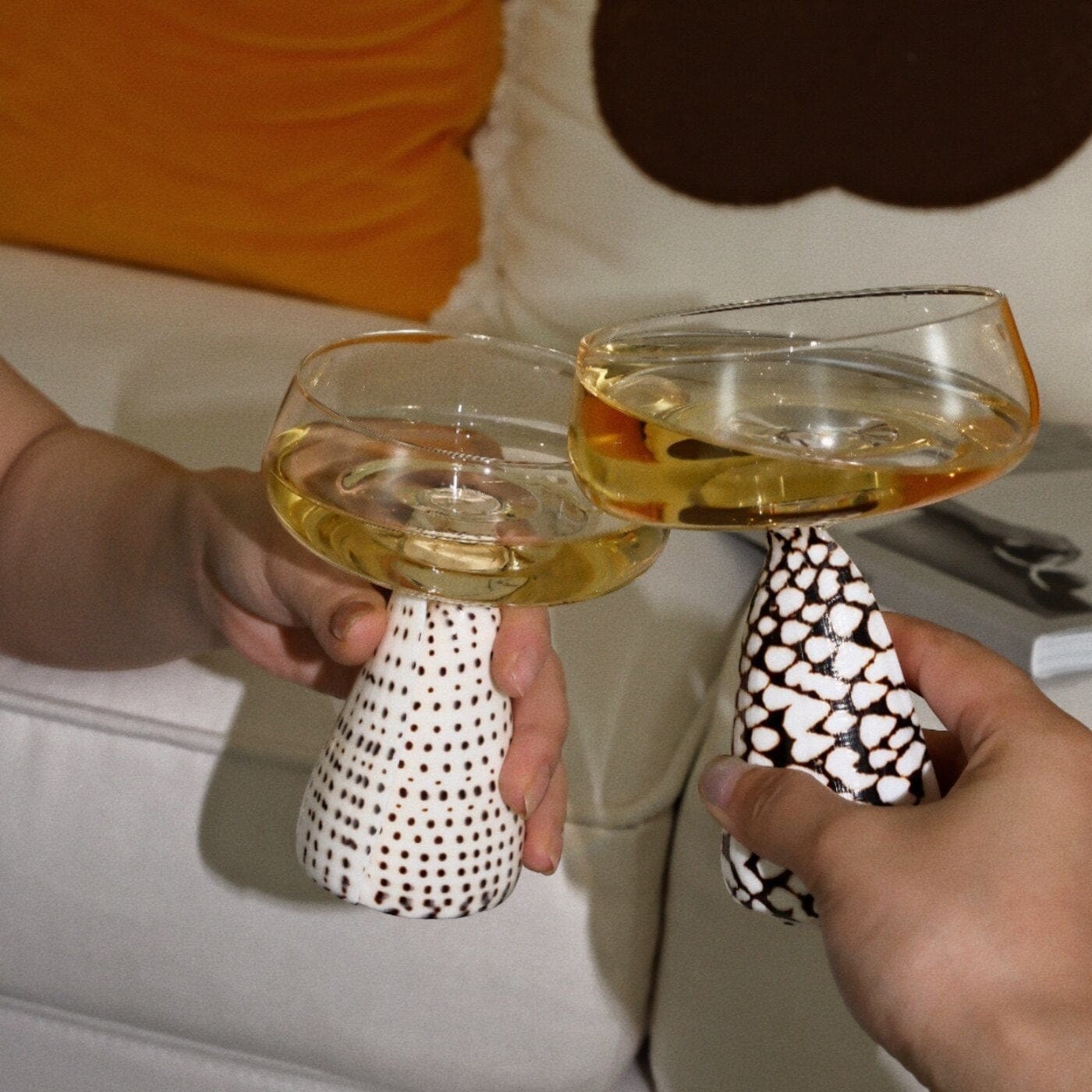 Two mushroom-shaped conch shell coupe glasses with clear glass bowls and white ceramic bases with black polka dots