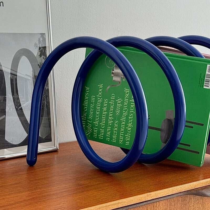 Blue curved spring book holder with glossy finish designed for stylish and functional book organization