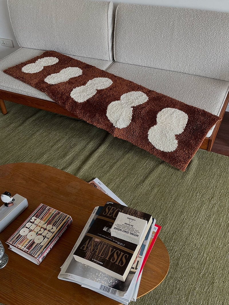 Minimal runner rug with brown plush material and cream-colored fluffy cloud-like patterns for indoor use