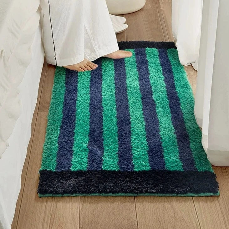 A plush green retro striped bath mat with alternating vertical stripes of vibrant green and deep navy blue