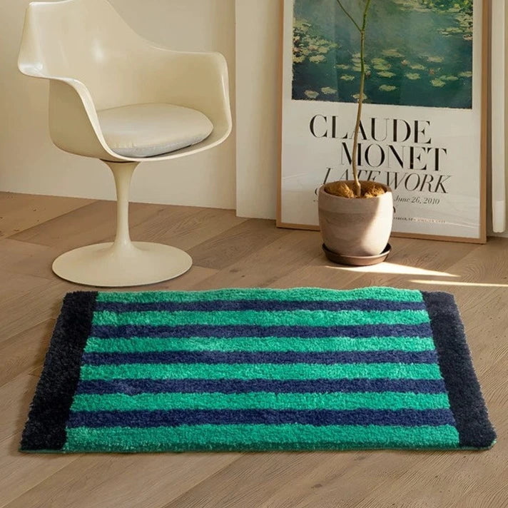 A plush green retro striped bath mat with vibrant teal and navy blue stripes and a soft textured surface