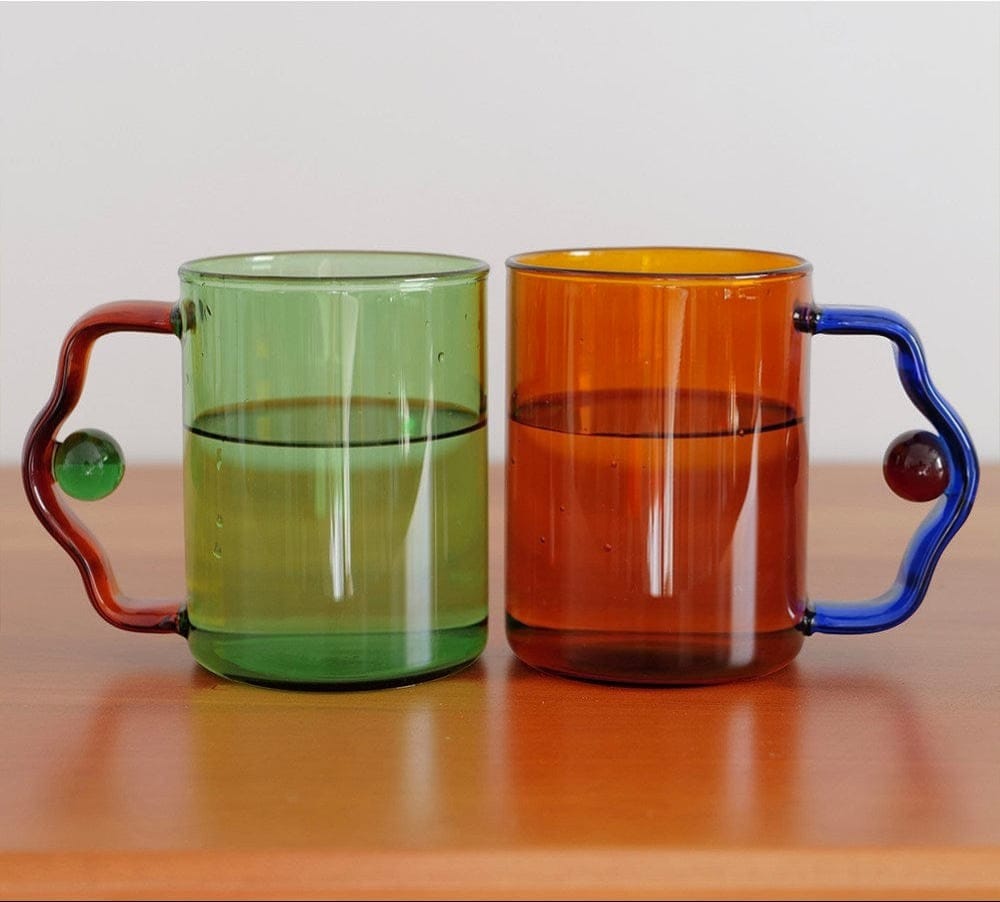 Two translucent glass color block bead mugs in green and amber orange with unique beaded handles