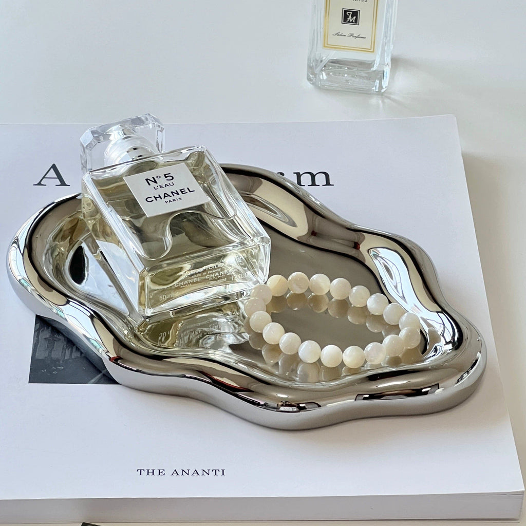 Shiny silver metallic ceramic cloud tray with organic wavy edges holding chanel no perfume bottle