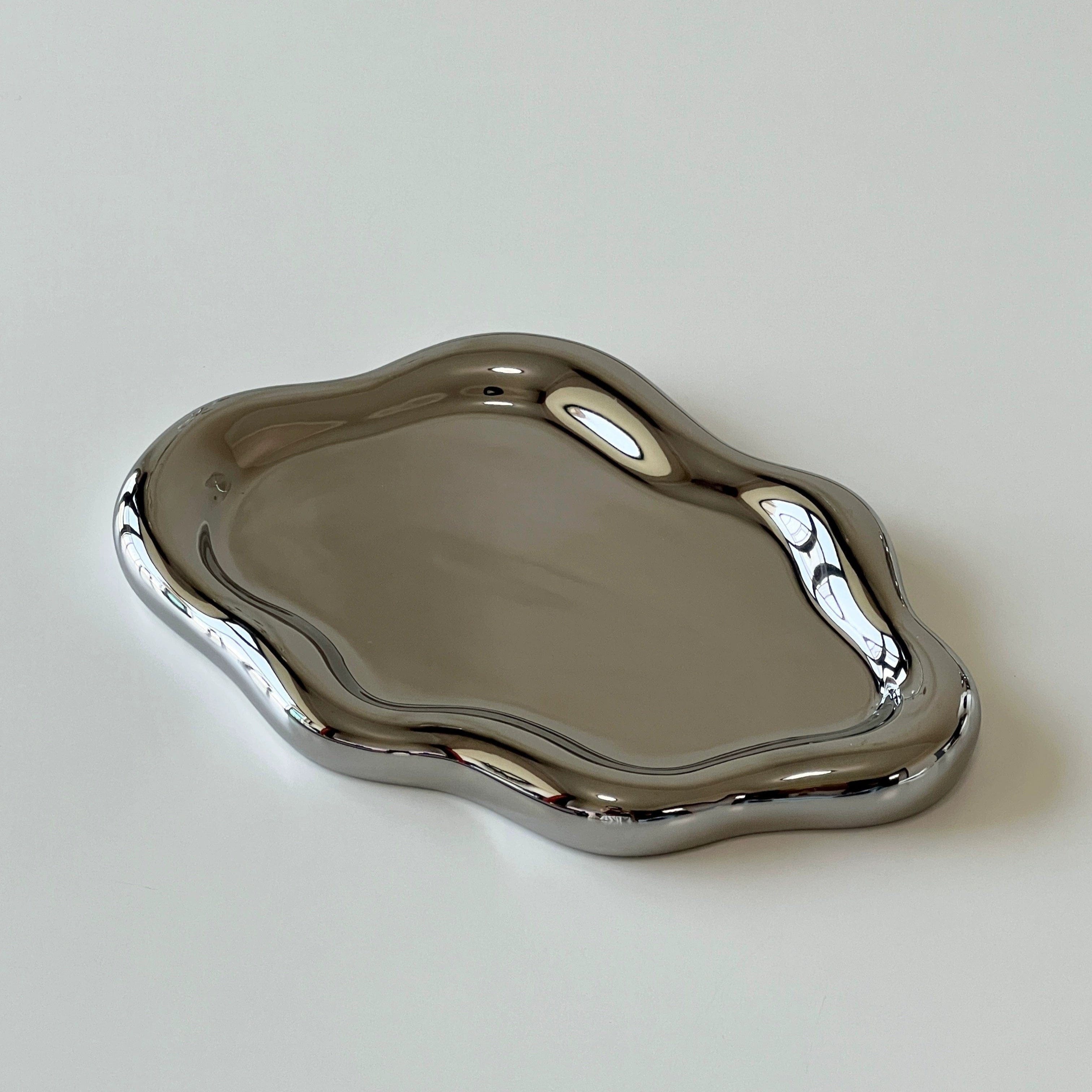 Shiny silver metallic ceramic cloud tray with a smooth wavy organic edge design for serving and display