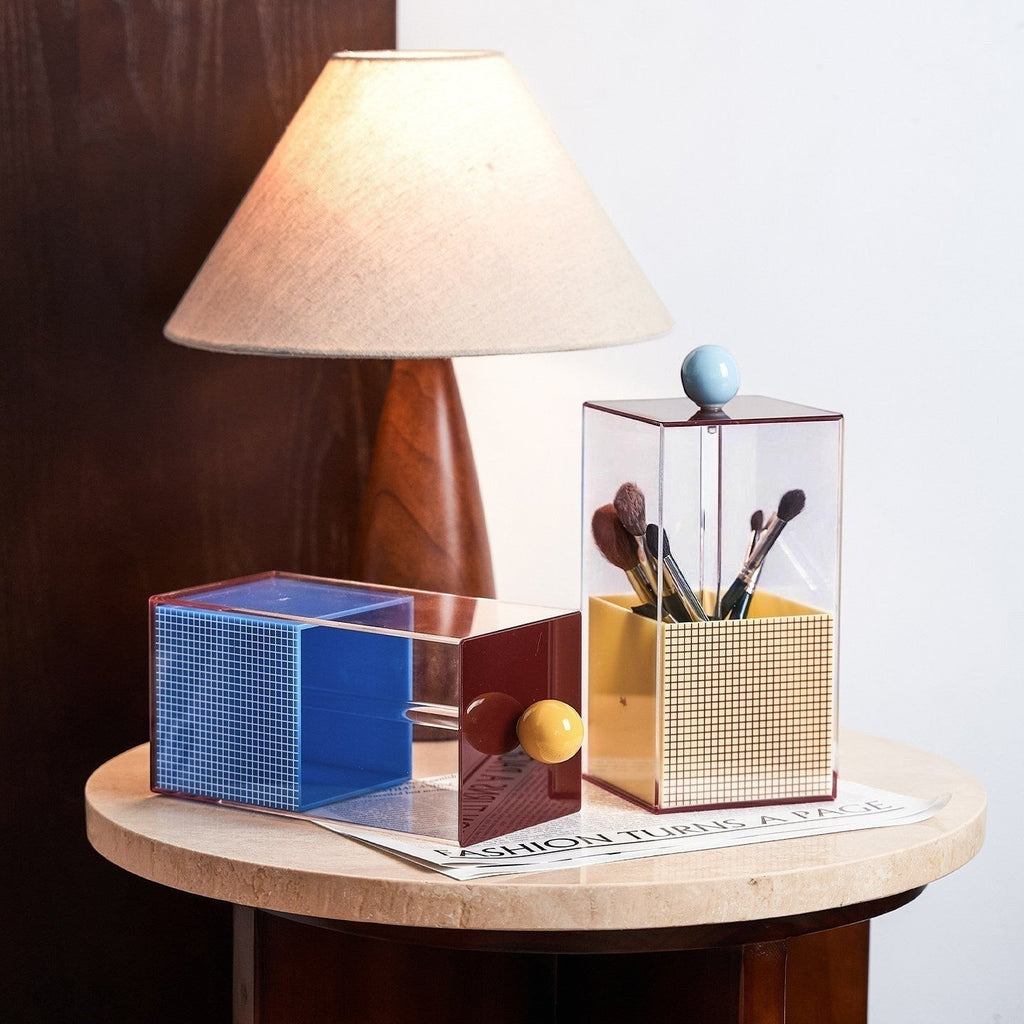 HOMELIVY acrylic brush holder in blue, red, and yellow with geometric grid pattern and yellow knob. Holds makeup brushes.