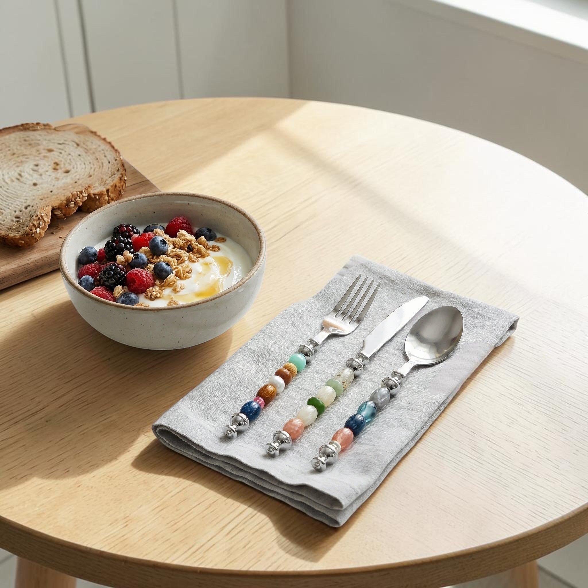 HOMELIVY beaded cutlery set featuring a fork, knife, and spoon with colorful gemstone-style handles on a grey napkin.