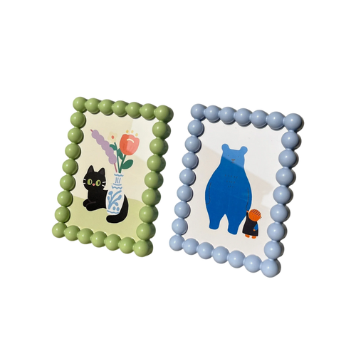 Two rectangular beaded retro picture frames with rounded corners in light green and light blue featuring cartoon illustrations