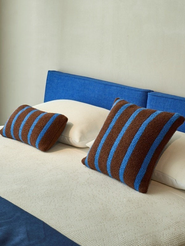 Striped boucle lumbar pillow and square cushion styled together on a bed