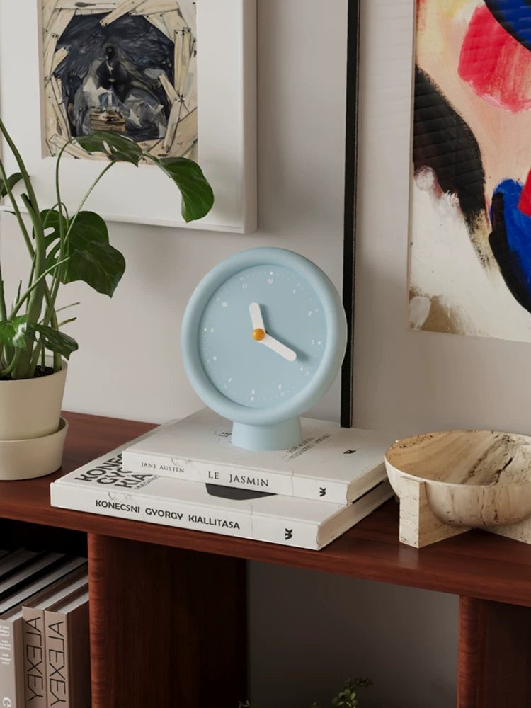 HOMELIVY powder blue minimalist desk clock with white hands and a pedestal base, displayed on books.