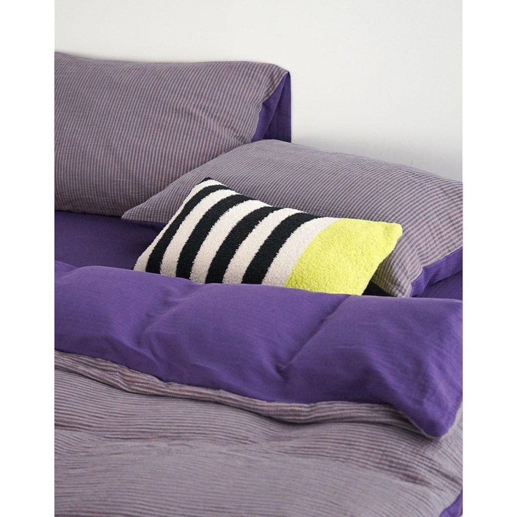 HOMELIVY Bouclé Stripe Lumbar Pillow with black, white, and lime green stripes on a bed with purple bedding.