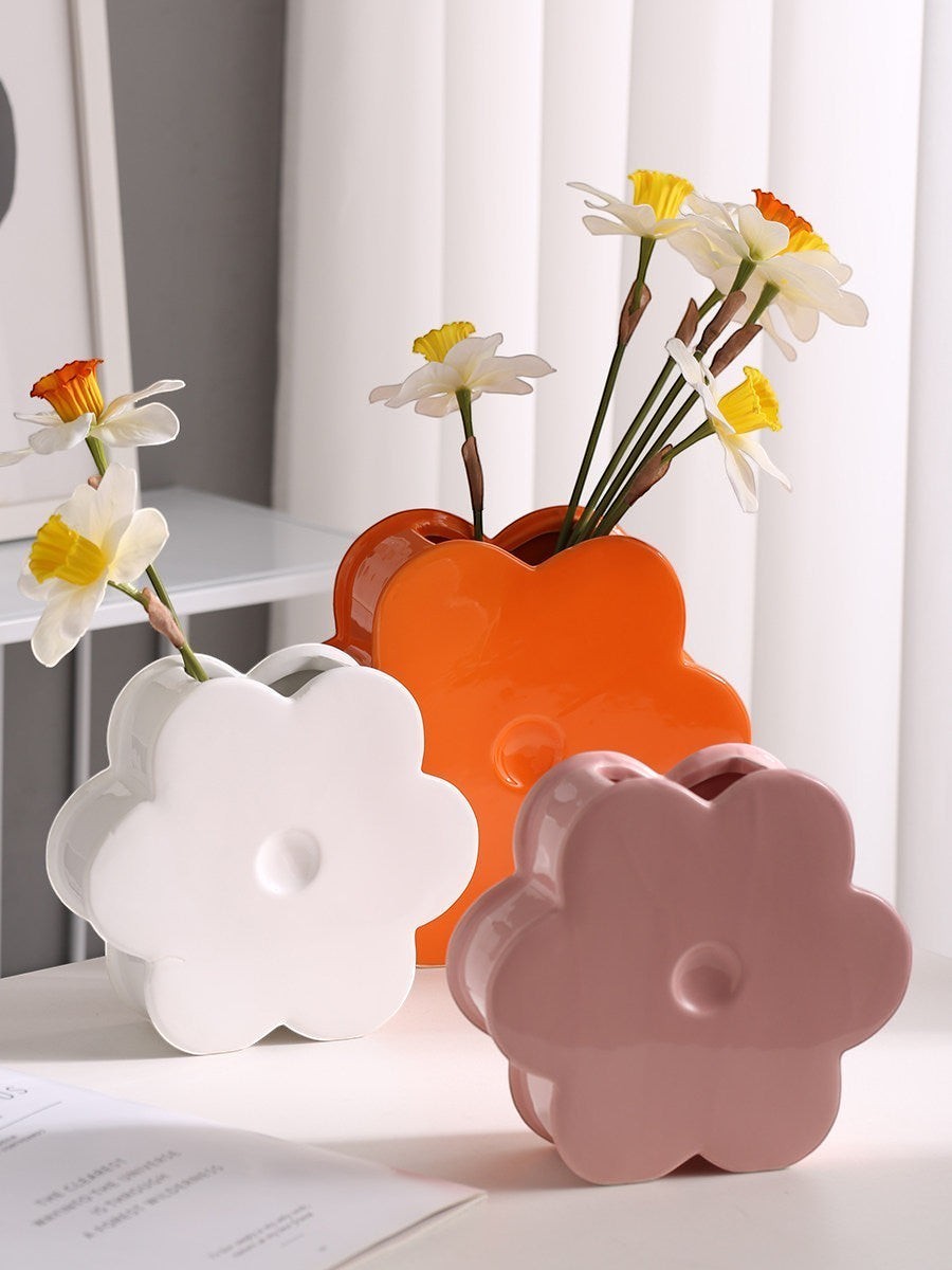 HOMELIVY ceramic flower-shaped vases in white, orange, and pink holding white and yellow daffodils on a table.