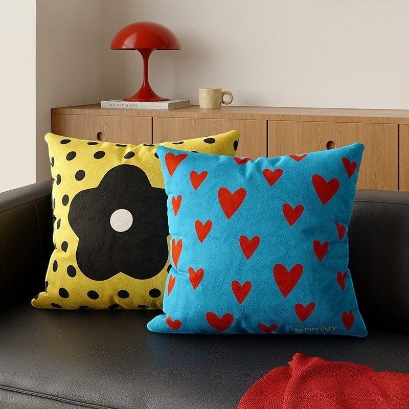 HOMELIVY decorative throw pillows featuring a yellow daisy flower pattern and a blue heart print on a black sofa.