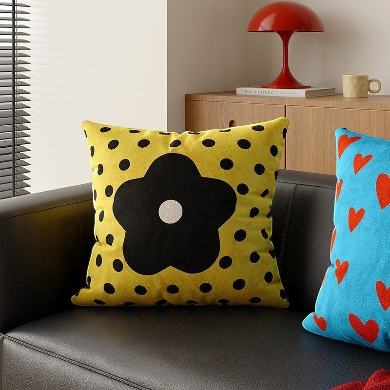 HOMELIVY yellow throw pillow with black polka dots and a large black daisy flower design on a modern sofa.