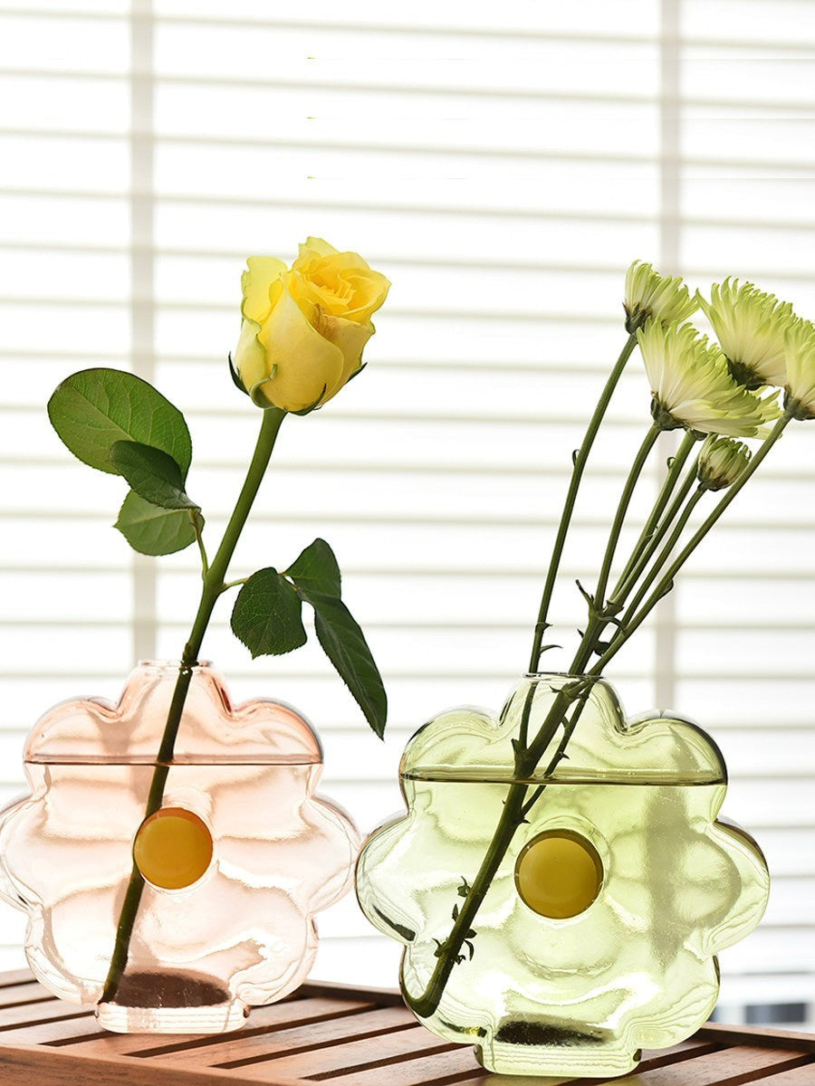 HOMELIVY flower-shaped glass vases in pastel pink and green with yellow centers holding fresh flowers.
