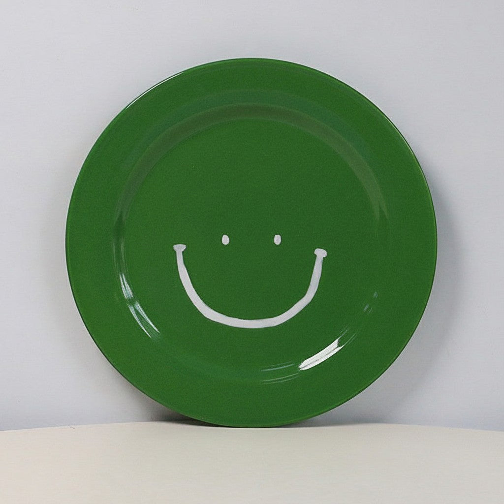 HOMELIVY green ceramic plate featuring a simple white hand-drawn smiley face design on a plain background