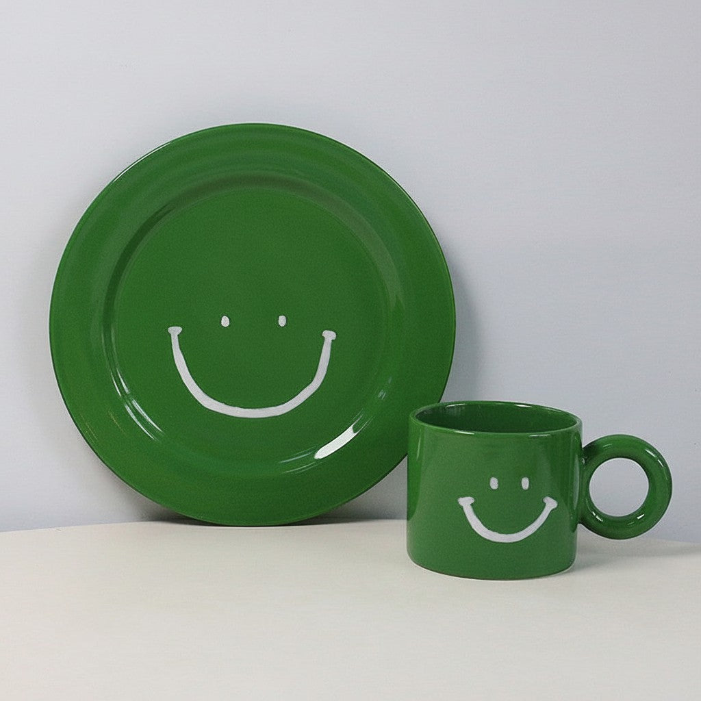 HOMELIVY green ceramic mug and plate set featuring a white hand-drawn smiley face design on each piece.