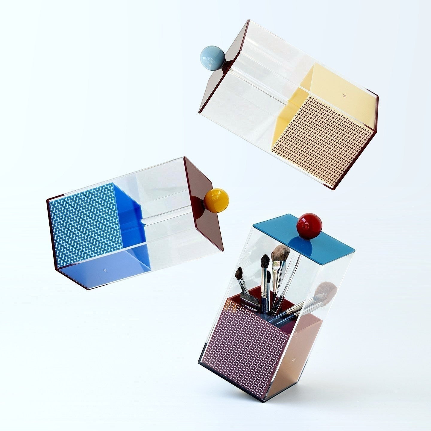HOMELIVY Quirky Memphis acrylic brush holder with blue, yellow, red, and pink geometric accents. Stores makeup brushes.