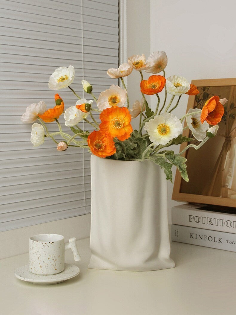 HOMELIVY white ceramic paper bag vase filled with orange and white artificial poppies on a desk