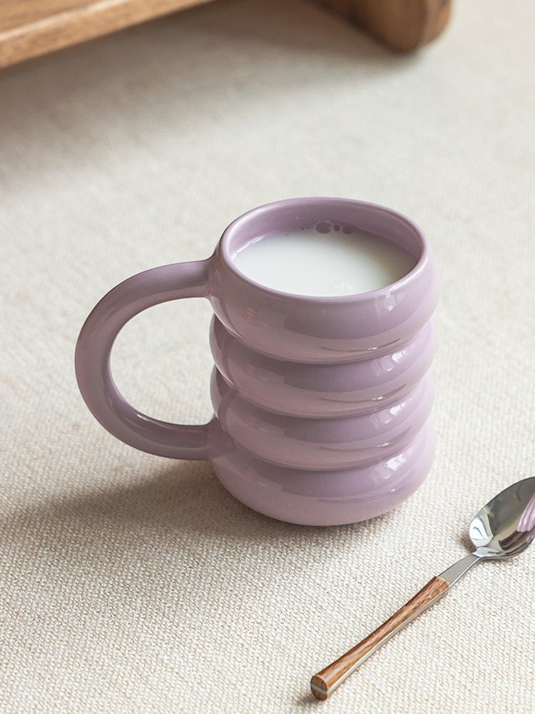 HOMELIVY pastel purple ceramic doughnut mug with a rounded ribbed design filled with milk on a textured surface
