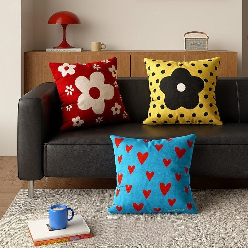 HOMELIVY decorative throw pillows with daisy, polka dot, and heart patterns in red, yellow, and blue on a sofa.