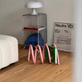 HOMELIVY pink spiral book holder with a wave design, holding a book on a wooden floor in a modern living room.