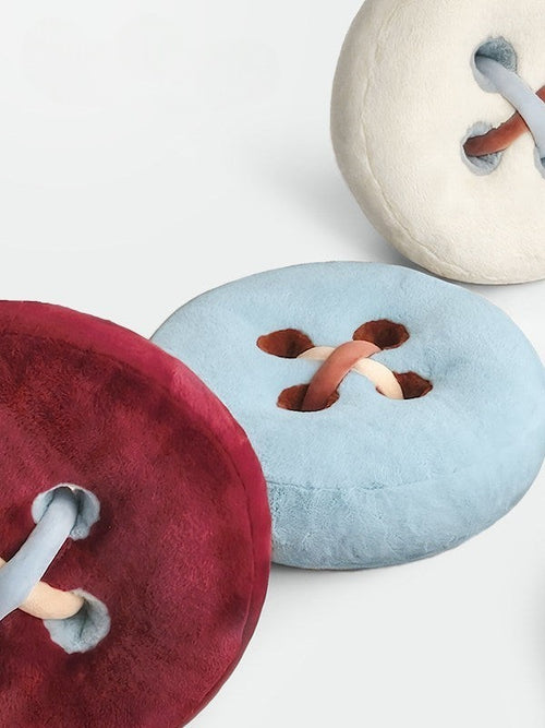 HOMELIVY plush button cushions in burgundy, light blue, and cream with braided thread detail.