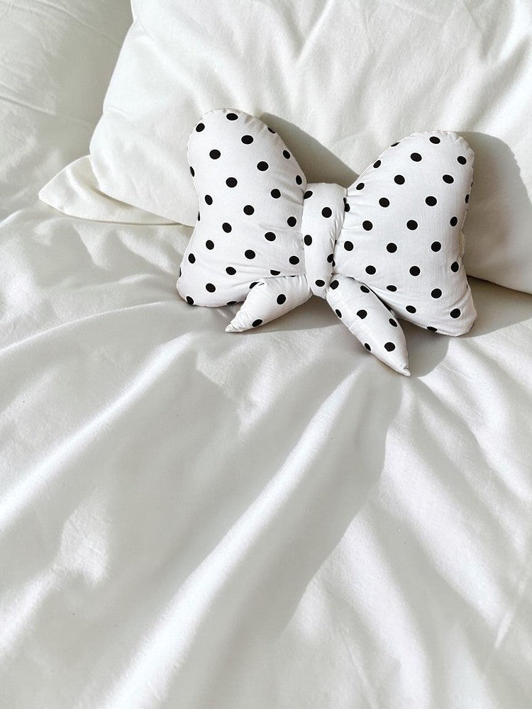 HOMELIVY white ribbon bow shaped cushion with black polka dots resting on a white bed sheet