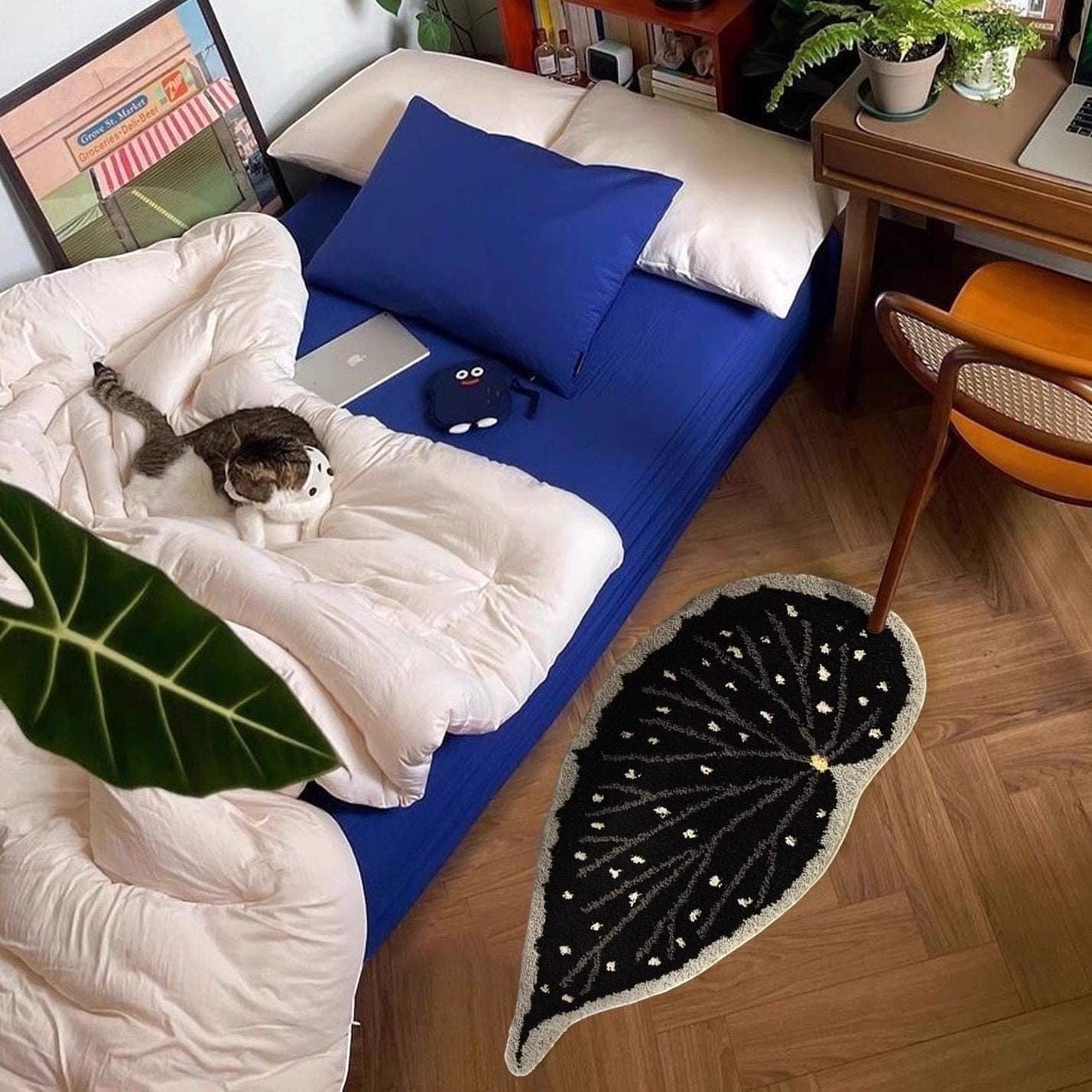 Room interior with a bed, laptop, and cat, featuring a leaf decorative rug on the floor.