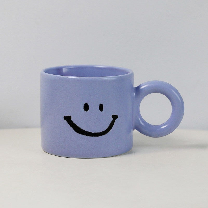 HOMELIVY light purple ceramic mug featuring a black hand-painted smiley face and a large circular handle.