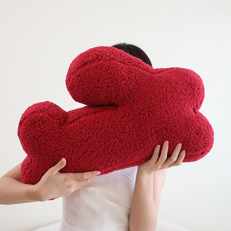 HOMELIVY plush red bone-shaped throw pillow with textured fabric, held by a person.