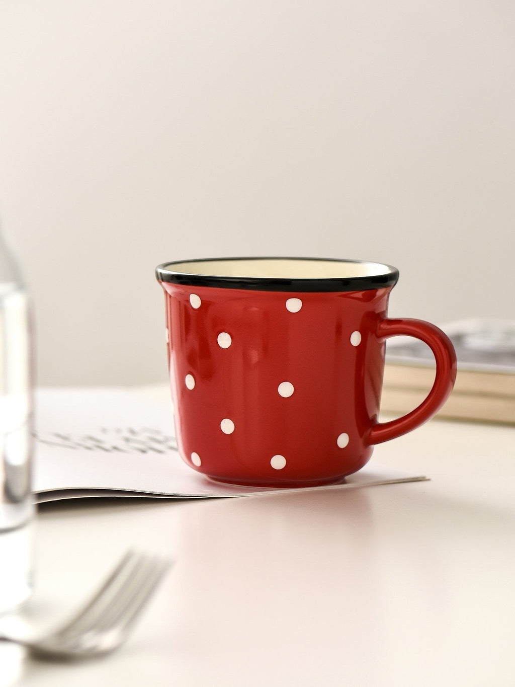 HOMELIVY retro ceramic mug in red with white polka dots and a black contrast rim on a white table