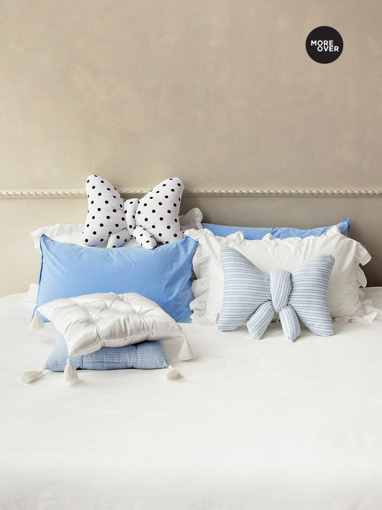 HOMELIVY ribbon bow shaped cushions in polka dot and blue striped patterns styled on a white bed with pillows