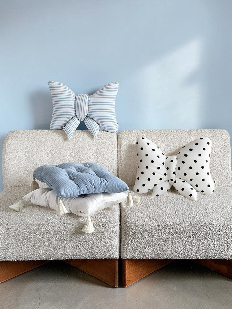 HOMELIVY ribbon bow shaped cushions in blue stripe and white polka dot patterns displayed on a textured sofa.