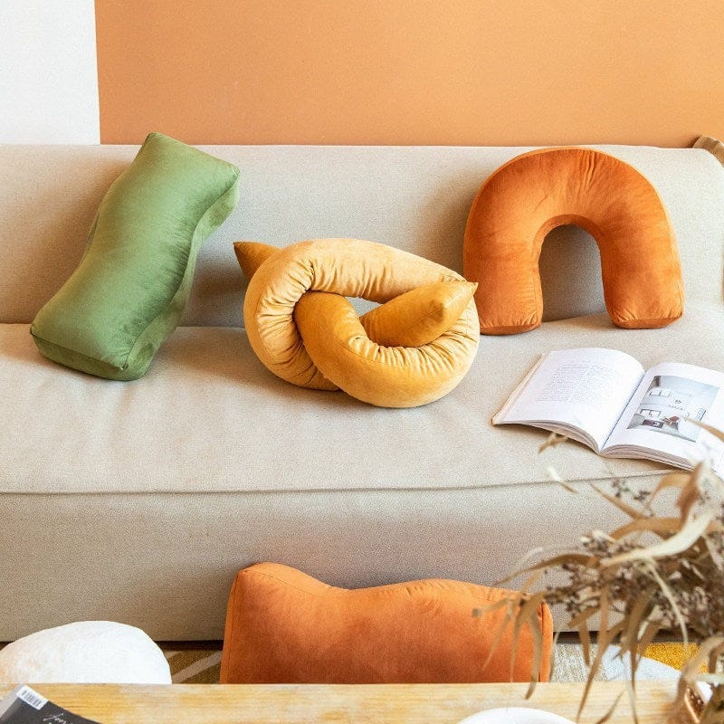 HOMELIVY velvet cushions: burnt orange arch, gold knot, olive bolster, and orange lumbar. Soft, sculptural shapes for sofa decor.
