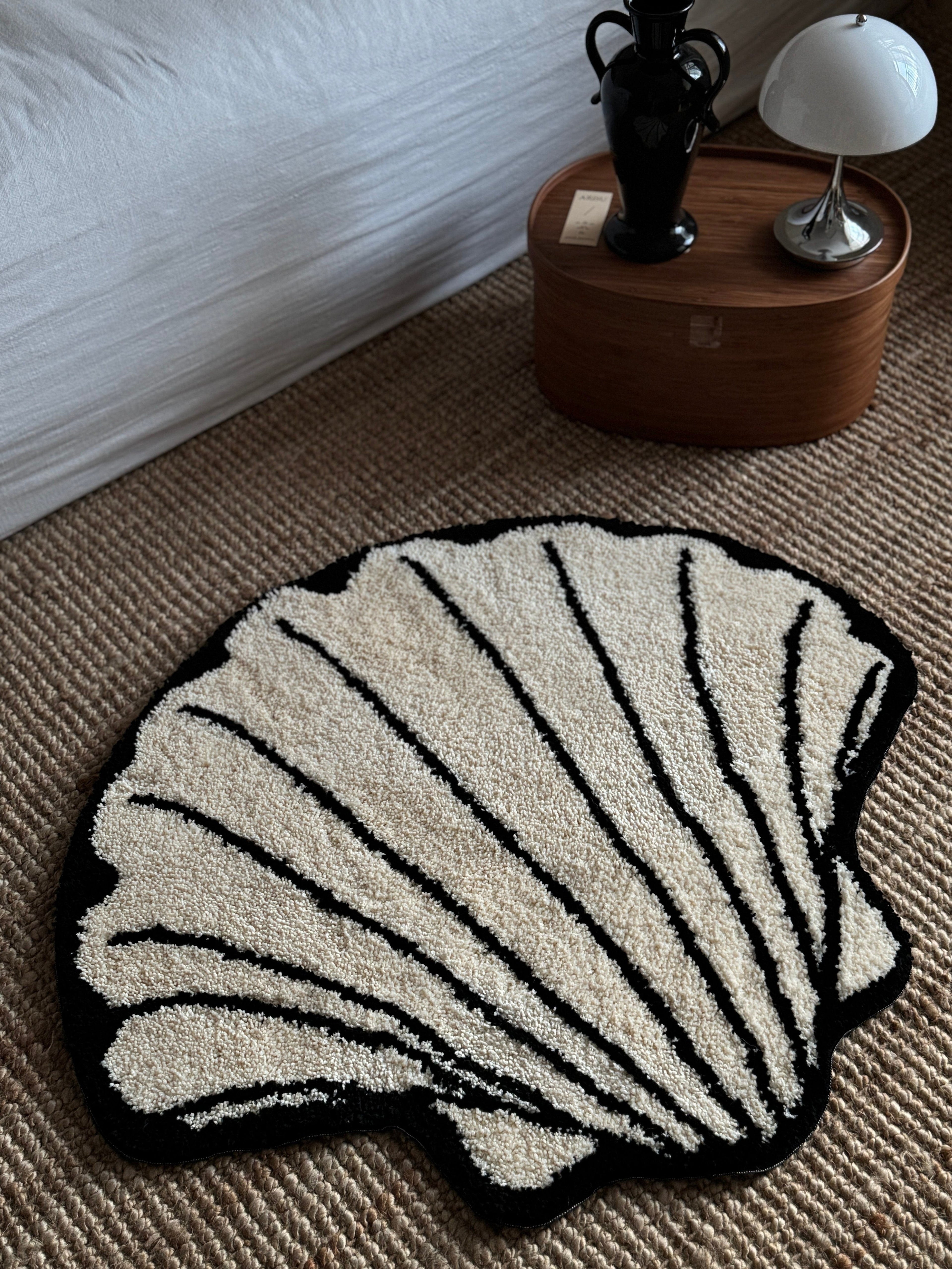 HOMELIVY cream and black shell-shaped tufted rug with textured surface and black outline.