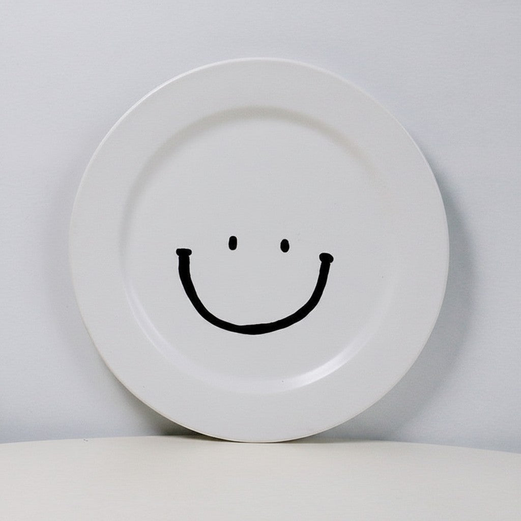 HOMELIVY white ceramic plate featuring a simple black hand-drawn smiley face design on a plain background