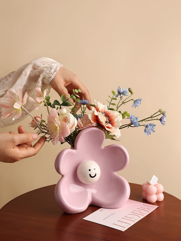 HOMELIVY ceramic flower-shaped vase in pastel pink with a cute smiley face center, holding a colorful floral bouquet.