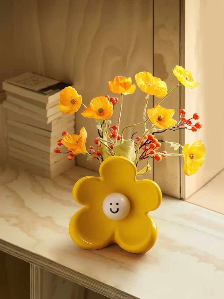 HOMELIVY yellow ceramic flower vase shaped like a daisy with a cute white smiley face center, holding yellow flowers.