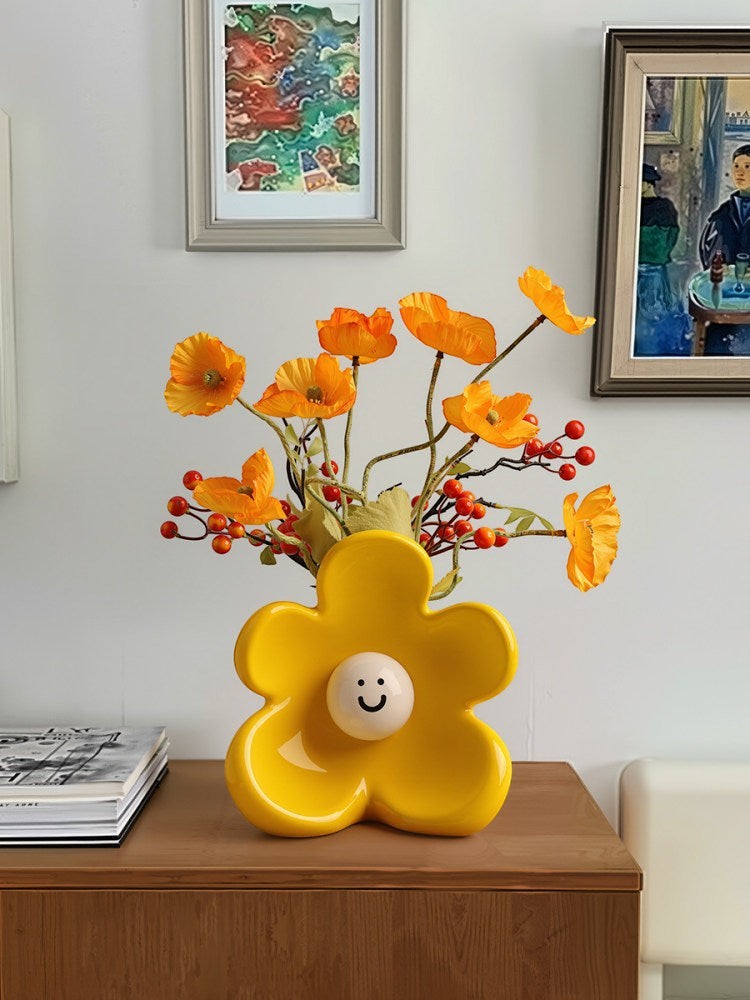 HOMELIVY yellow ceramic flower-shaped vase with a cute smiley face center, holding orange poppy flowers.