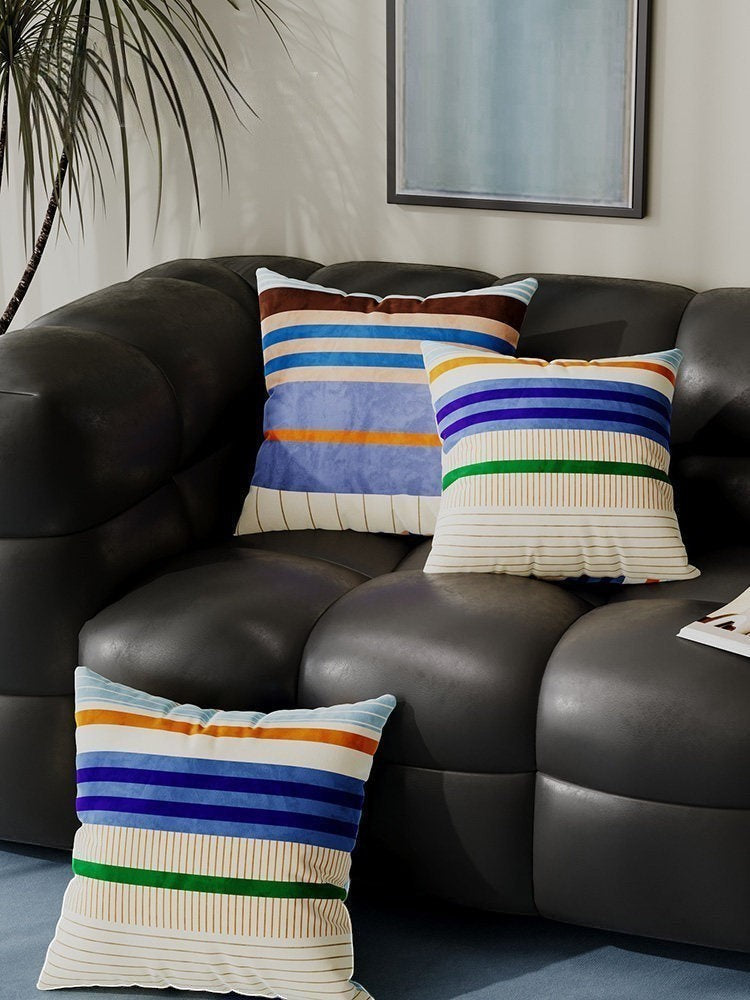 HOMELIVY colour block stripe cushion covers in velvet with blue, orange, and green patterns on a dark leather sofa.