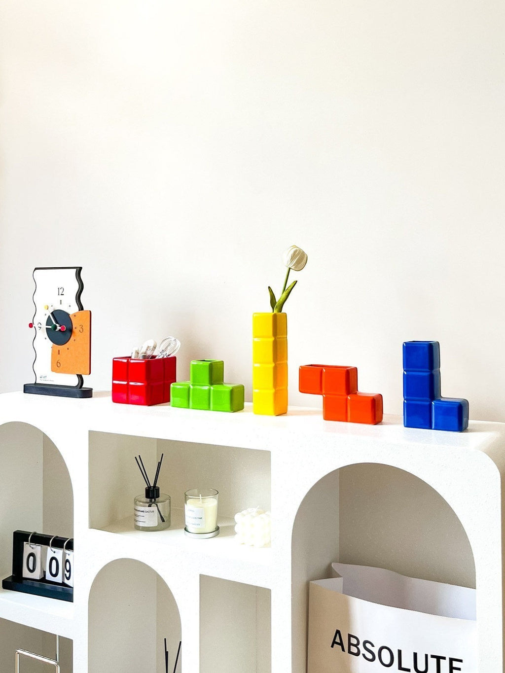 HOMELIVY Tetris-inspired ceramic vases in vibrant glossy primary colors displayed on a modern white arched shelf.