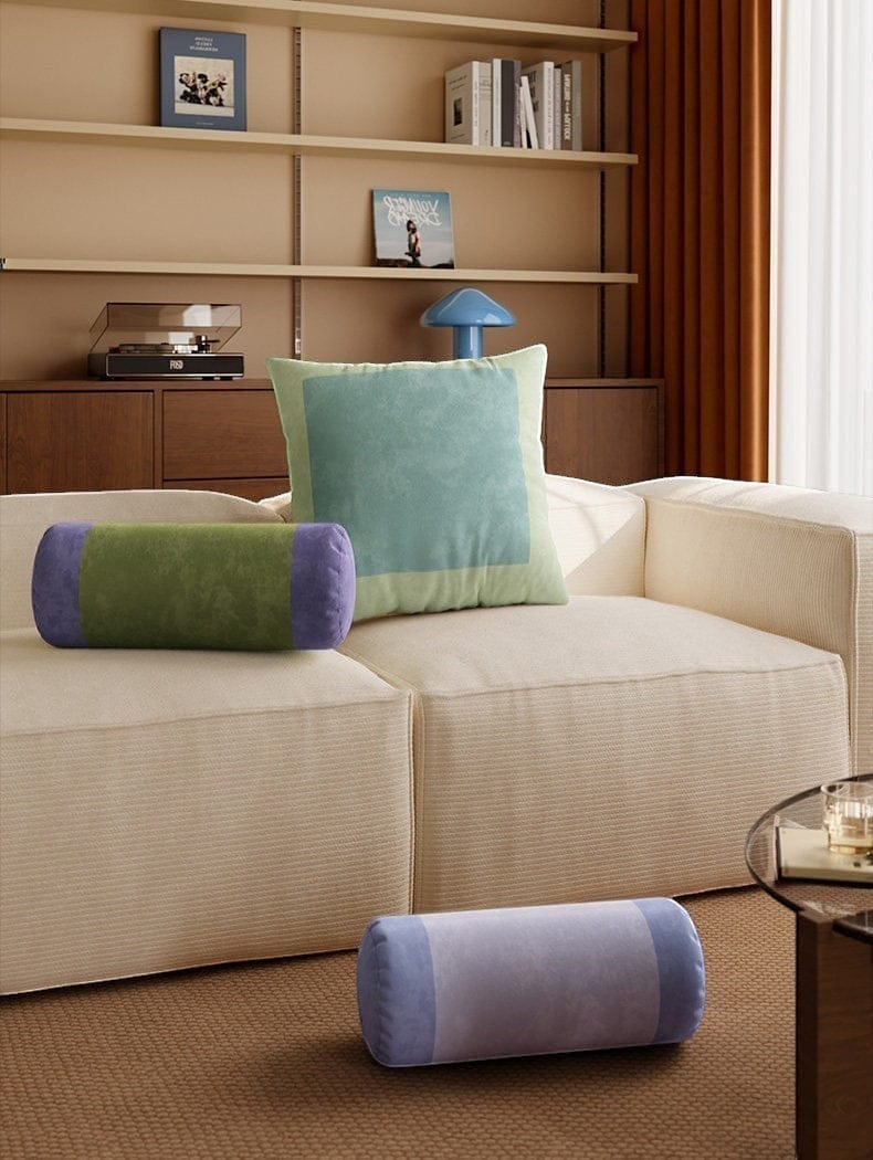 Beige corduroy sofa with a light green and purple velvet retro striped bolster pillow on its seat