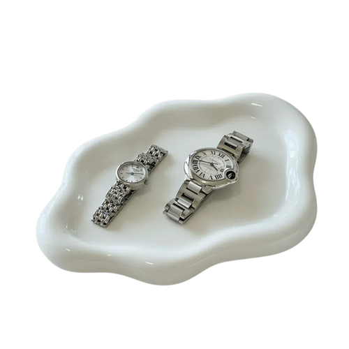 Ceramic cloud tray holding two silver-toned wristwatches with metallic links and white dials one with roman numerals