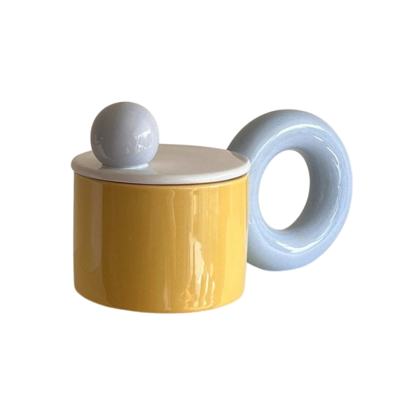 HOMELIVY ceramic mug with a yellow body, light blue donut-shaped handle, and a white lid with a spherical knob.