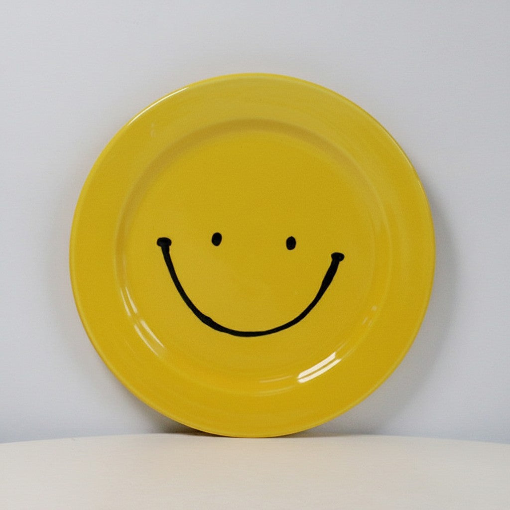 HOMELIVY yellow ceramic plate featuring a black hand-drawn smiley face design on a white background