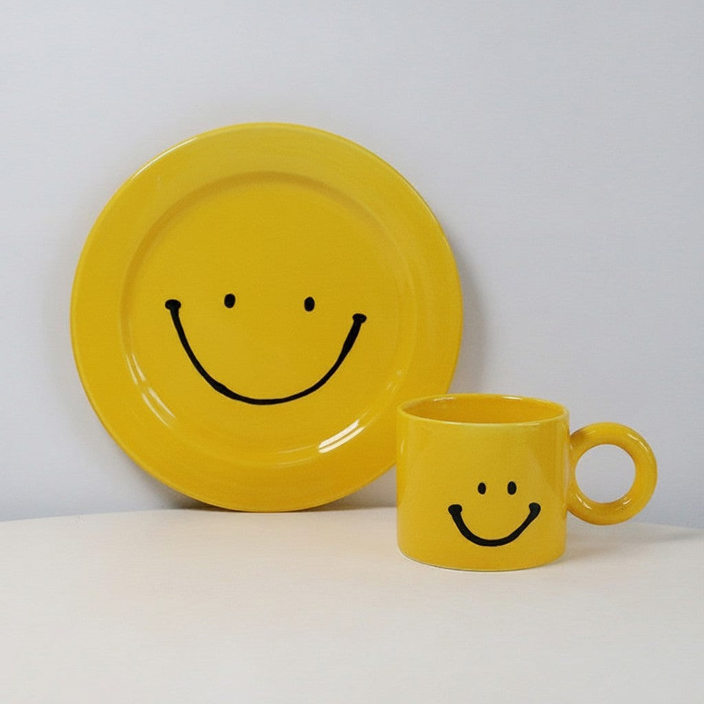 HOMELIVY yellow ceramic mug and plate set featuring a black smiley face design on a white background.